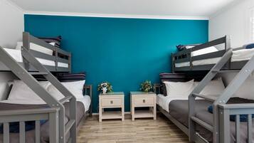 Een kamer met stapelbedden, een klein nachtkastje met een plant, en een muur in een effen teal kleur.