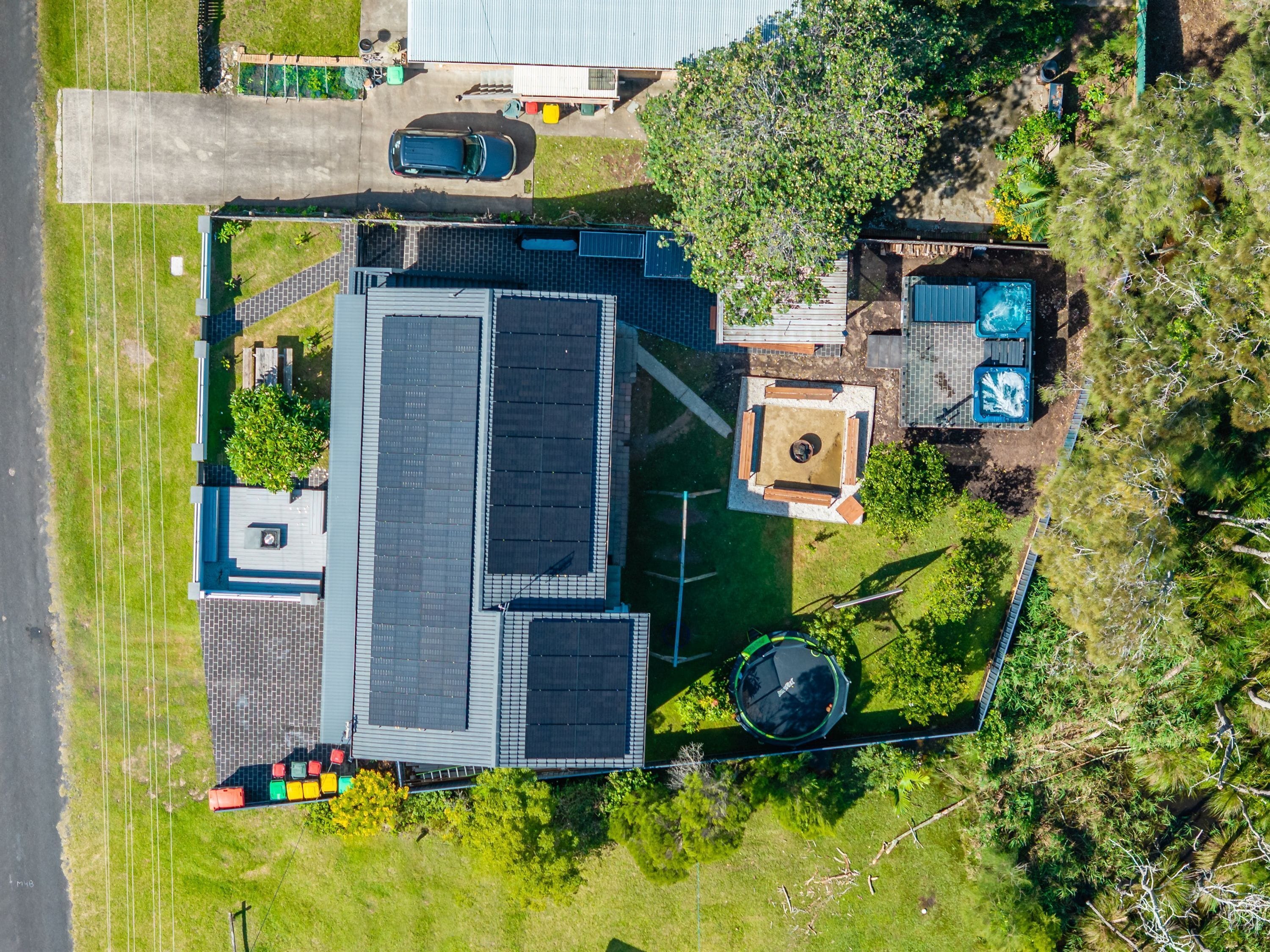Een woonhuis met een groot gebouw, zonnepanelen, een zwembad en een trampoline.