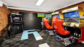 Um quarto com jogos de corrida de fliperama, uma televisão de tela grande e um padrão de piso xadrez.