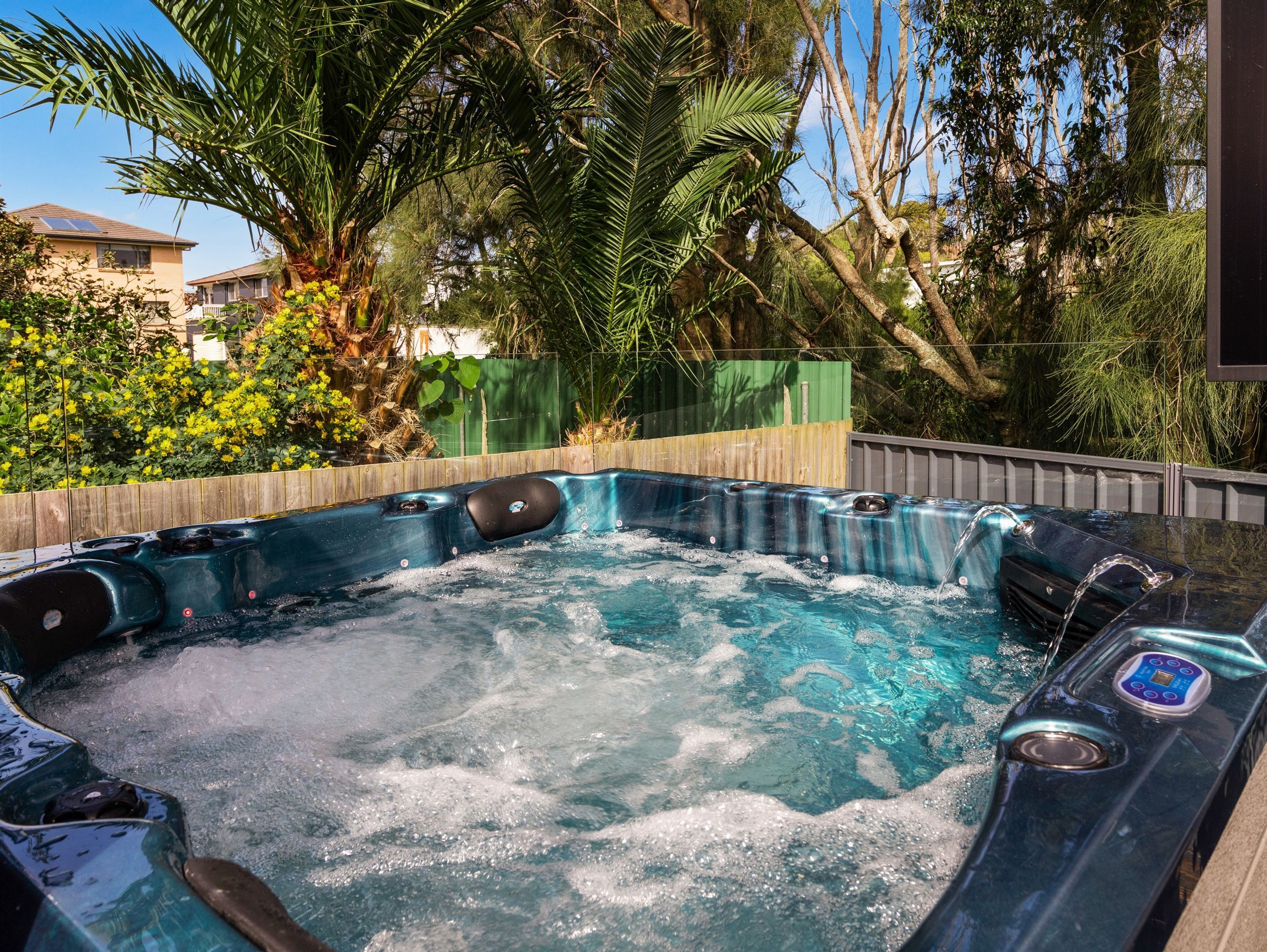 Ein Whirlpool mit einer Holzterrasse und Blick auf eine Wohngegend mit Häusern und Bäumen.