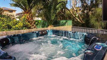 Ein Whirlpool mit einer Holzterrasse und Blick auf eine Wohngegend mit Häusern und Bäumen.
