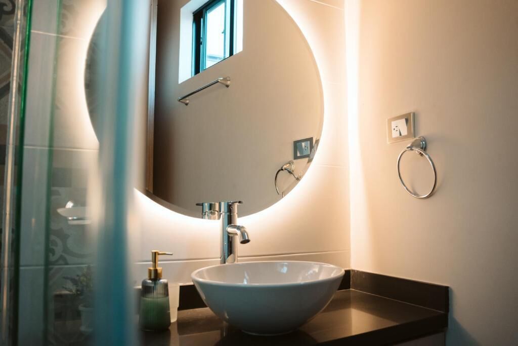 A bathroom with a round mirror, a sink, and a towel ring.