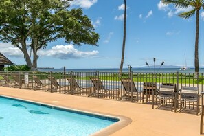 Ein Poolbereich mit Liegestühlen und Blick auf das Meer.