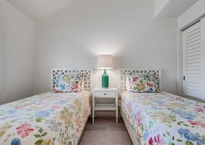 Ein Schlafzimmer mit zwei Betten, einem Nachttisch, einer Lampe und einem Kleiderschrank.