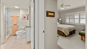A bedroom with a bed, a window with blinds, a ceiling fan, and a bedside table. - Beachfront 4BR, 2 Condos for 12 at Maalaea Surf! (Kihei)