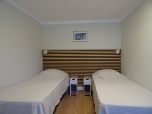 A room with two single beds, a wooden headboard, a small bedside table, and a wall-mounted picture. - Charming, detached garden-level vacation rental near the town center (Neuvic)