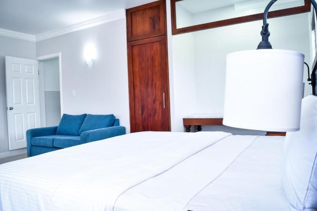 Ein Hotelzimmer mit einem Bett, einem blauen Sofa, einem Holzschrank und einem Nachttisch mit Lampe.