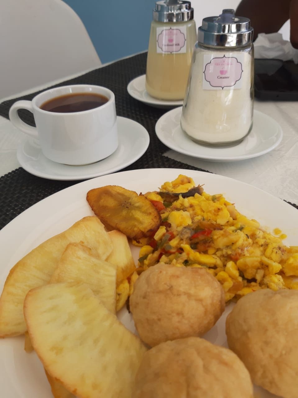Un piatto con cibo, una tazza di caffè e due bottiglie di salse su un tavolo.