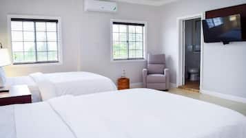 A hotel room with two beds, a television, a chair, and a window.