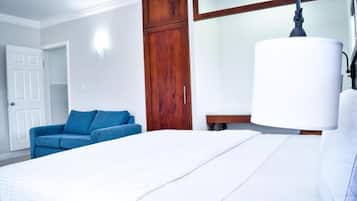 A hotel room with a bed, a blue sofa, a wooden wardrobe, and a bedside table.
