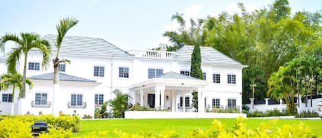 A large, white two-story house with a covered porch and a well-maintained garden.