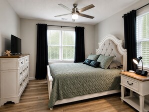 A bedroom with a bed, a dresser, a nightstand, a ceiling fan, and a window with curtains. - Video Game Hub, Hot Tub, PS5, Xbox, Switch, Pool Table, Air Hockey, Fire Pit (Valdosta)