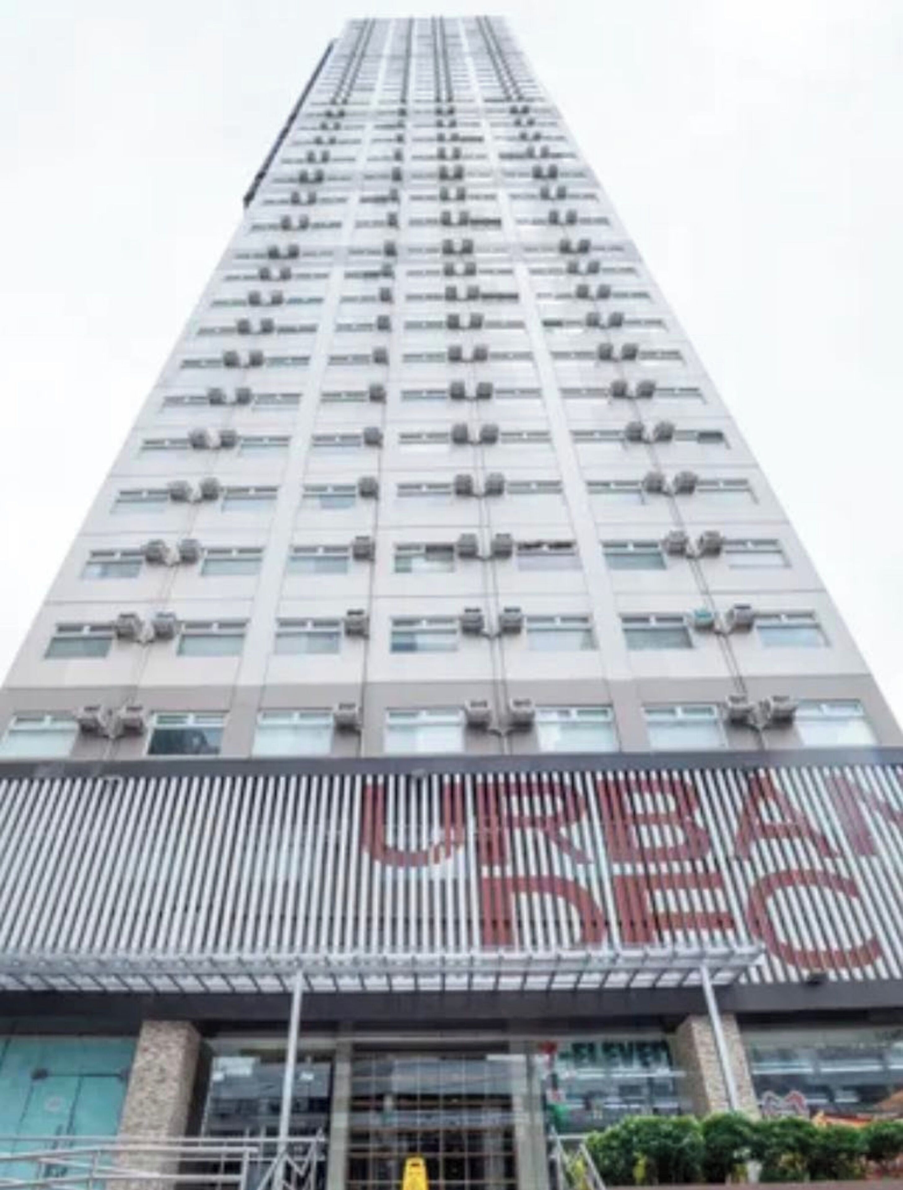 A high-rise building with multiple floors, air conditioning units on each window, and a large, bold sign on the lower level.
