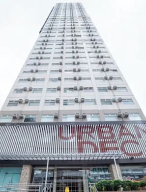 A high-rise building with multiple floors, air conditioning units on each window, and a large, bold sign on the lower level. - Cozy Stay at Urban Deca Towers Cubao (Quezon City)