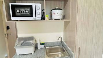 A compact kitchenette with a microwave, slow cooker, and a small sink.