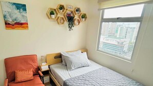 Une chambre à coucher comprenant un lit, une chaise, une table de chevet, une horloge murale, une fenêtre et un tableau.