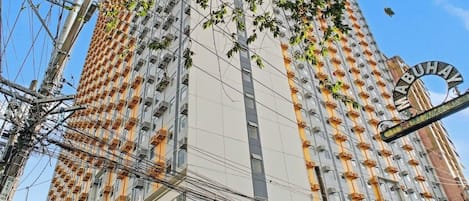Un edificio de gran altura con varios balcones, una escalera y un letrero que indica el nombre 'MABUHA'.