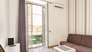 A living room with a sofa, a table, a sliding glass door leading to a balcony, and a TV on a stand. - Elegantis Campo Marzio Apartment With Terrace | Spanish Steps, Trevi & Pantheon (Roma)