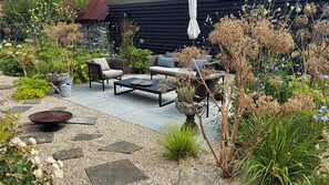 A garden patio with outdoor furniture, a metal bowl, and various plants.
