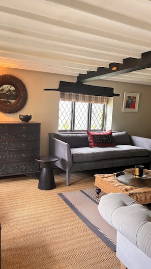 A cozy living room with a sofa, a coffee table, a side table, and a decorative mirror.