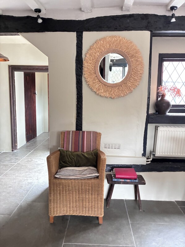 A room with a wicker chair, a small table with books, a mirror, and a window with a view.