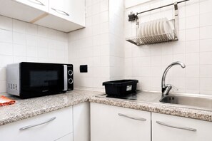 A kitchen with white cabinets, a microwave, a sink, and a dish rack. - Elegantis Campo Marzio Penthouse With Terrace | Spanish Steps, Trevi & Pantheon (Roma)