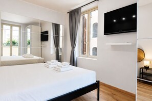 Una habitación de hotel moderna con una cama grande, un televisor de pantalla plana en la pared y una ventana con cortinas.