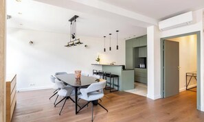 A modern interior with a dining table, chairs, a kitchen area, and a hallway. - AN EXCEPTIONAL AUTHENTIC PARISIAN CHARM WITH PRIVATE COURTYARD -SAINT GERMAIN (Paris)