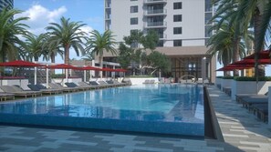 A swimming pool with lounge chairs and umbrellas, surrounded by palm trees and a modern building. - near Bayfront Park Deluxe Room , Pet - friendly (Miami)