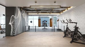 Ein geräumiger Fitnessraum mit Trainingsgeräten, einem Sandsack und Wandmalerei.