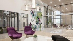 Eine geräumige Lobby mit zeitgemäßer Einrichtung, großen Fenstern und einem farbenfrohen, abstrakten Kunstwerk.