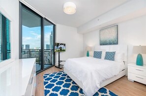 Quarto moderno com uma cama grande, televisão e vista para a cidade através de uma porta deslizante.