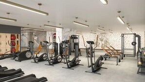 Un gimnasio moderno con diversos equipos de ejercicio, como cintas de correr, bicicletas estáticas y máquinas de pesas.