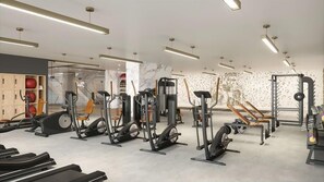 Ein modernes Fitnessstudio mit verschiedenen Trainingsgeräten, darunter Laufbänder, Ergometer und Kraftgeräte.