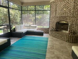 A room with a brick fireplace, a sectional sofa, and a large window overlooking a forest. - SASADEERLODGE 6-bedroom house with AC in Richmond Hill (Richmond Hill)