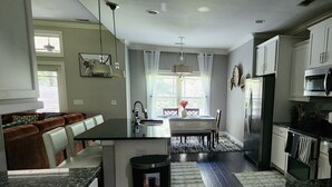 A modern kitchen with a central island, built-in appliances, and a dining area with a view. - SASADEERLODGE 6-bedroom house with AC in Richmond Hill (Richmond Hill)