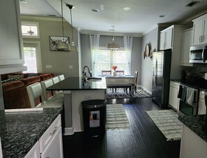 A modern kitchen with a central island, built-in appliances, and a dining area with a view. - SASADEERLODGE 6-bedroom house with AC in Richmond Hill (Richmond Hill)
