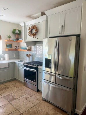 A modern kitchen with white cabinetry, a stainless steel refrigerator, and a gas stove. - Superb 3-bedroom home in peaceful Atascadero (Atascadero)