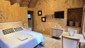 Una habitación con paneles de madera, una cama, un escritorio y un televisor.