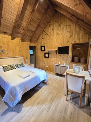 A wooden-paneled room with a bed, a desk, and a television. - Cabañas en el bosque de Puerto Manzano (Puerto Manzano)