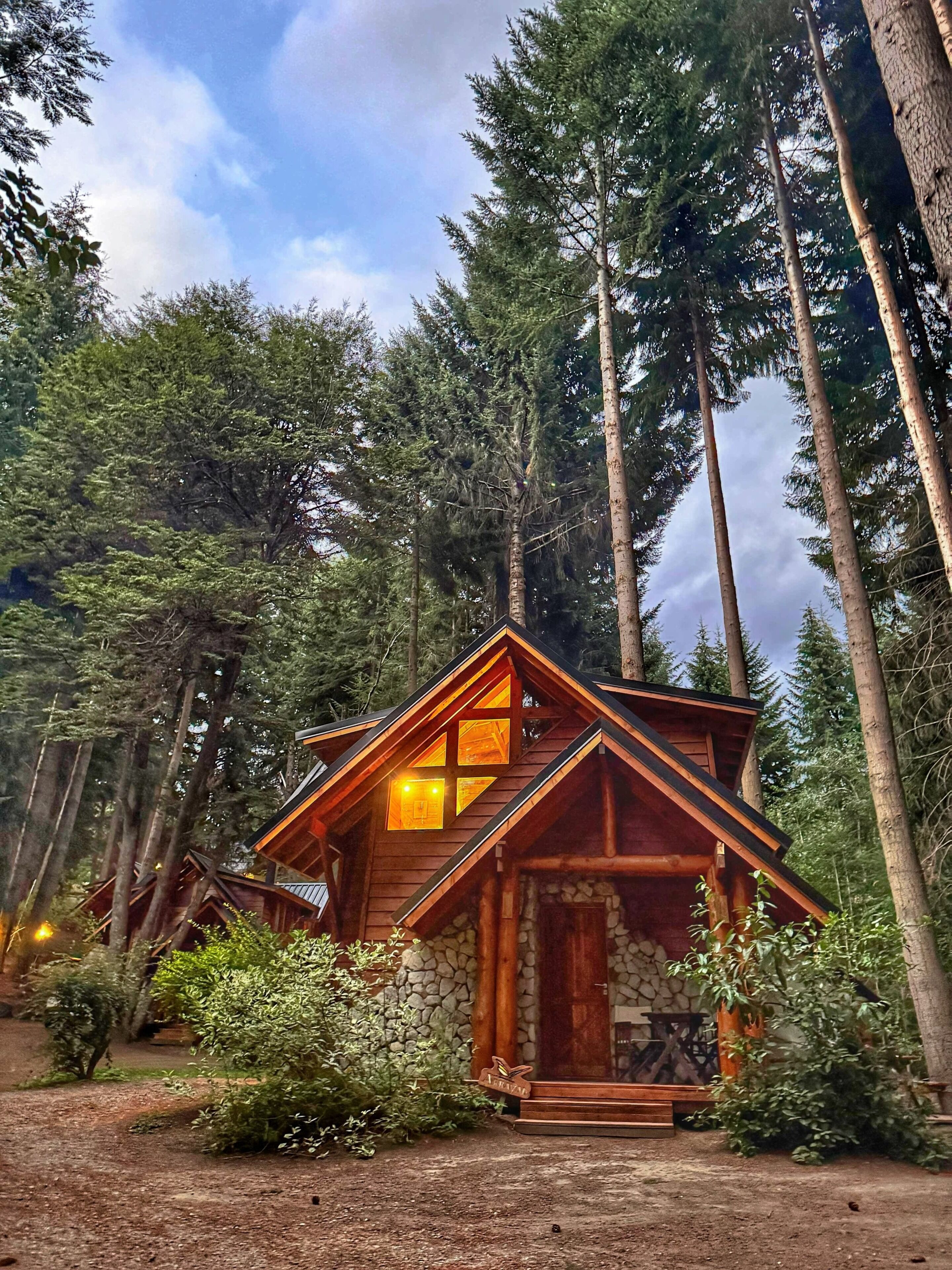 Uma cabana com base de pedra, fachada de madeira e uma janela grande.