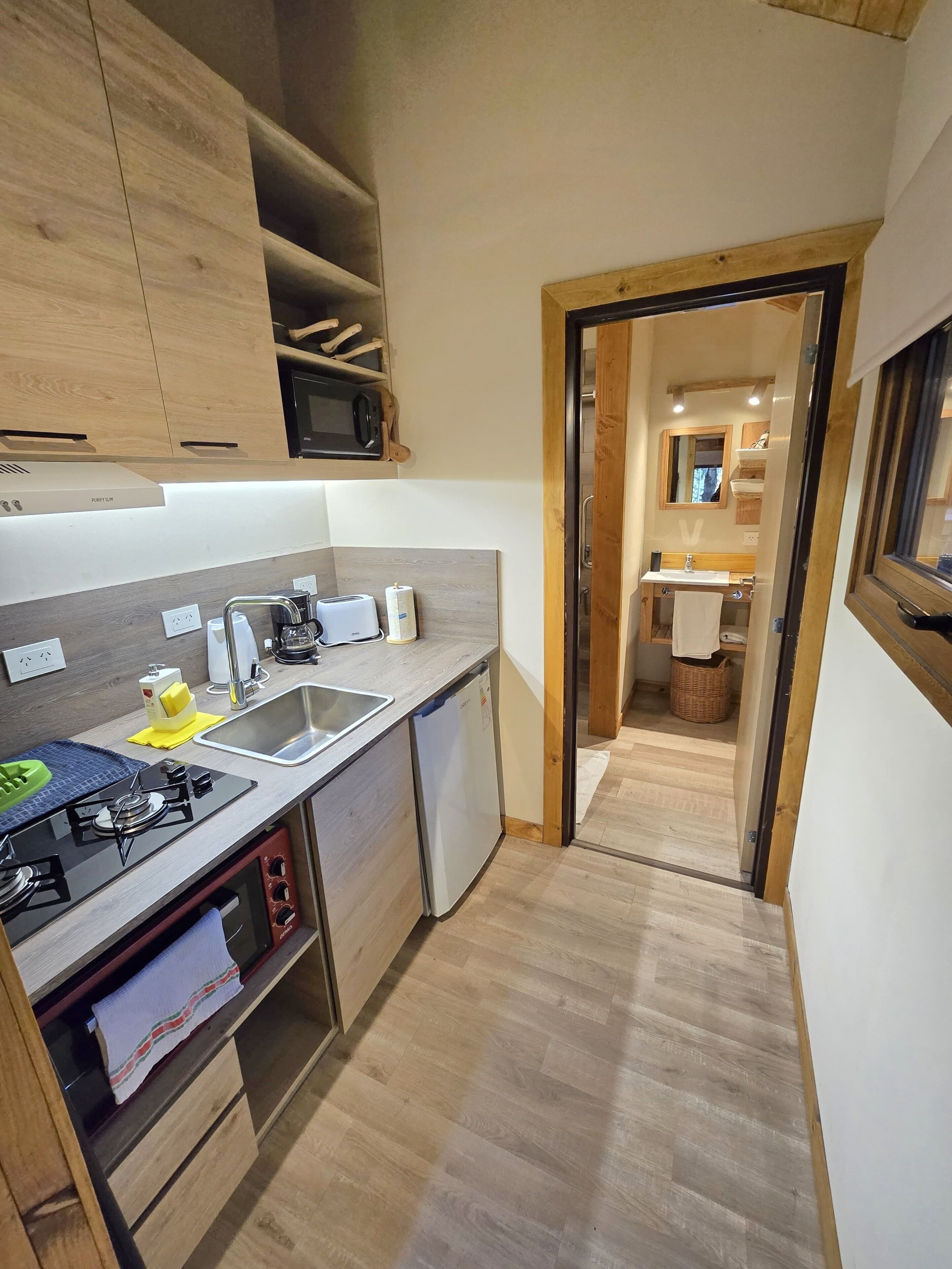 Une cuisine de taille réduite, équipée d’une cuisinière intégrée, d’un évier et d’un réfrigérateur compact.