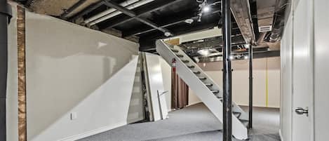 A stairwell with a metal staircase, a white door, and exposed ceiling beams.