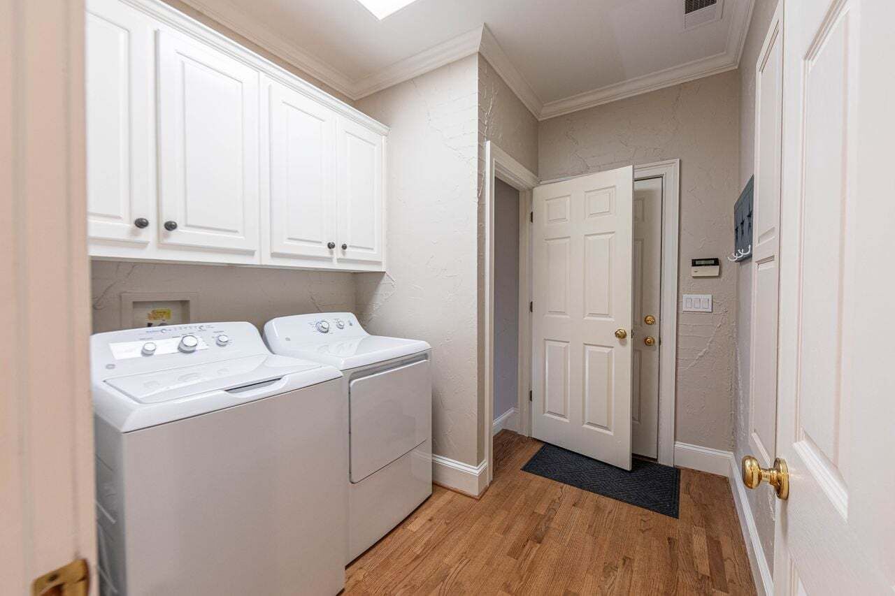 A laundry room with a washer and dryer, a door with a doorknob, and a wall-mounted thermostat.