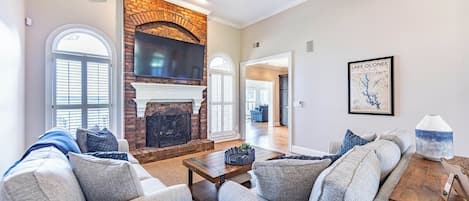 A living room with a fireplace, a ceiling fan, and a map of Lake Oconee on the wall.