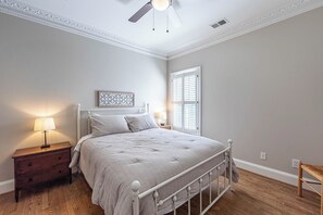 A bedroom with a bed, nightstand, lamp, and a window with shutters. - Lakefront 4BR retreat with deck, kayaks, many dining areas, and cozy fireplace. (Eatonton)