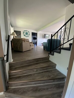Eine Treppe führt zu einem Wohnbereich mit einer Couch und einem Fernseher.