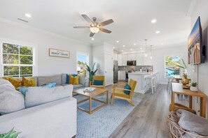 A modern living room with a sofa, coffee table, and a dining area with chairs. - Welcome to Banana Villa,Waterfront,Golf Cart,Kayak,New Home (North Myrtle Beach)