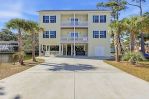 A two-story building with a covered front porch and a garage. - Welcome to Banana Villa,Waterfront,Golf Cart,Kayak,New Home (North Myrtle Beach)