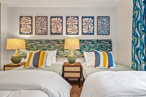 Ein Hotelzimmer mit zwei Betten, einem großen, abstrakten Gemälde an der Wand und einem gemusterten Vorhang.